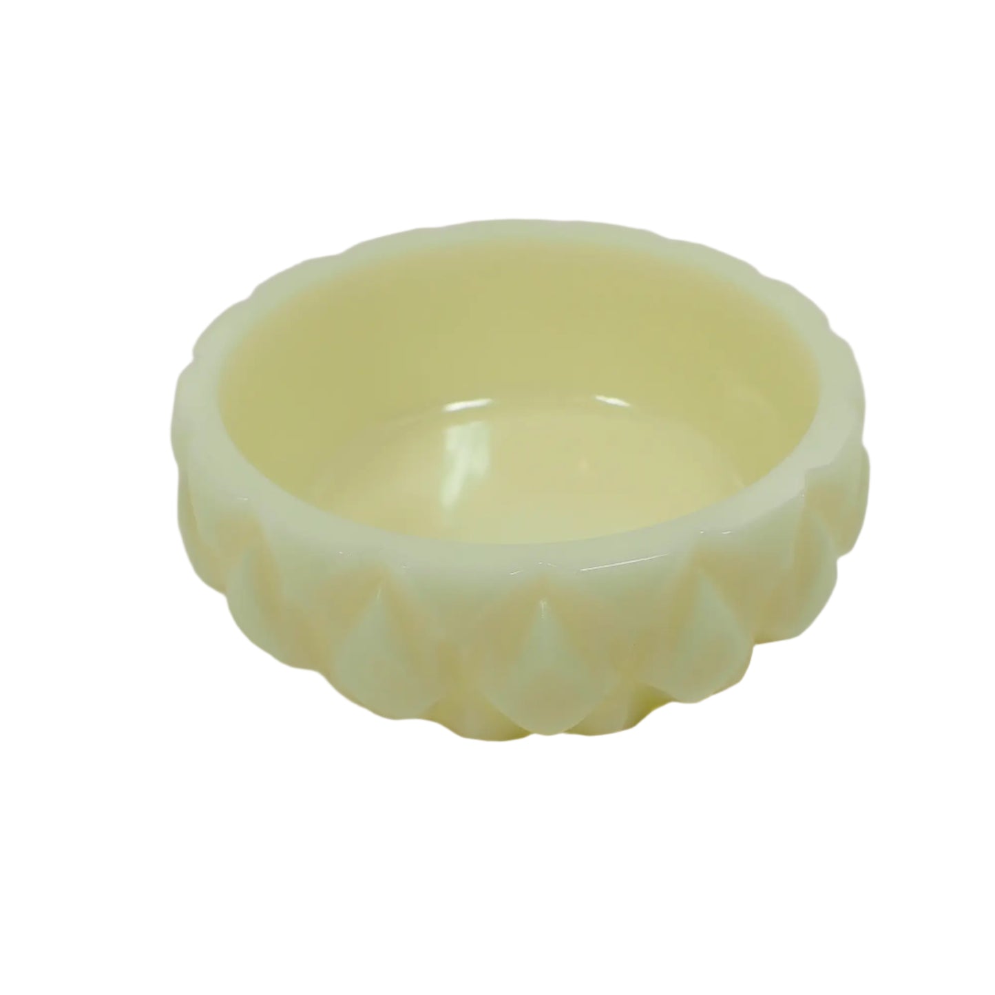 Angled side view of the handmade ring dish. It is short and round with a faceted diamond shape pattern around the outside edge. The resin is a very light lemon cream pastel yellow in color.