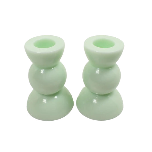 Angled view of the handmade resin candle holders. They are a light green lime cream color and have a geometric round shape.