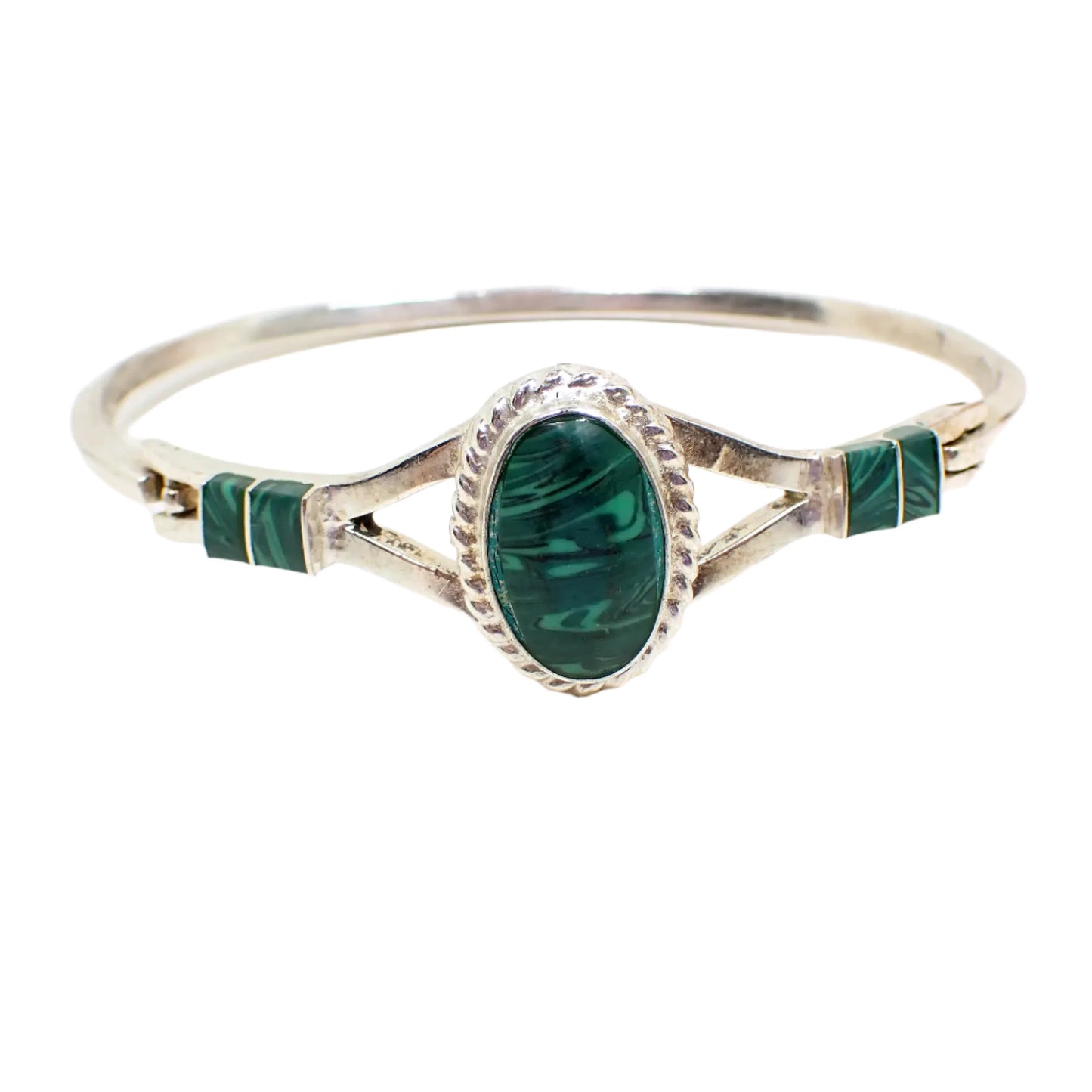 Front view of the vintage Mexican gemstone hinged bangle bracelet. The metal is silver tone in color. There is an oval on the front and two rectangles on either side that have slices of malachite gemstone atop of green resin. The gemstone has swirls of different shades of green.