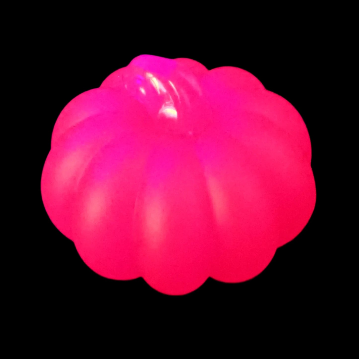 Photo of the neon pink resin pumpkin under a UV light fluorescing bright pink in color.