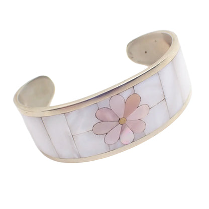 Angled view of the vintage cuff bracelet. The sections of inlaid mother of pearl shell can be seen clearly. The flower petals have light dyed pink pieces and the rest is pearly white.