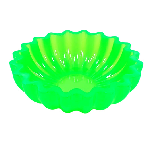 Angled side view of the large handmade neon green resin bowl. The resin is shiny and semi translucent in a bright neon green color that has hints of yellow as the light shines through it. It is round with fluted side and a scalloped top edge. Great for storing small items, as a succulent planter pot, as part of a table centerpiece, or just added to your UV fluorescent home decor.