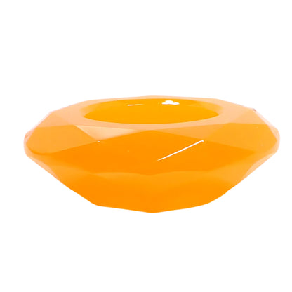 Side view of the handmade neon orange resin faceted round decorative bowl. It's shaped similar to a large faceted gemstone and has an opening at the top.