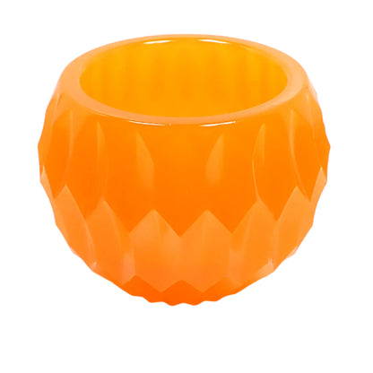 Angled side view of the handmade neon orange resin succulent pot decorative bowl. It is round with an indented hexagon shape all the way around it. There is a round opening at the top.