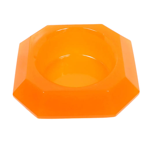 Angled view of the handmade resin bowl. It has an octagon shape and semi translucent bright neon orange resin. There is an opening at the top to put small things such as succulents.