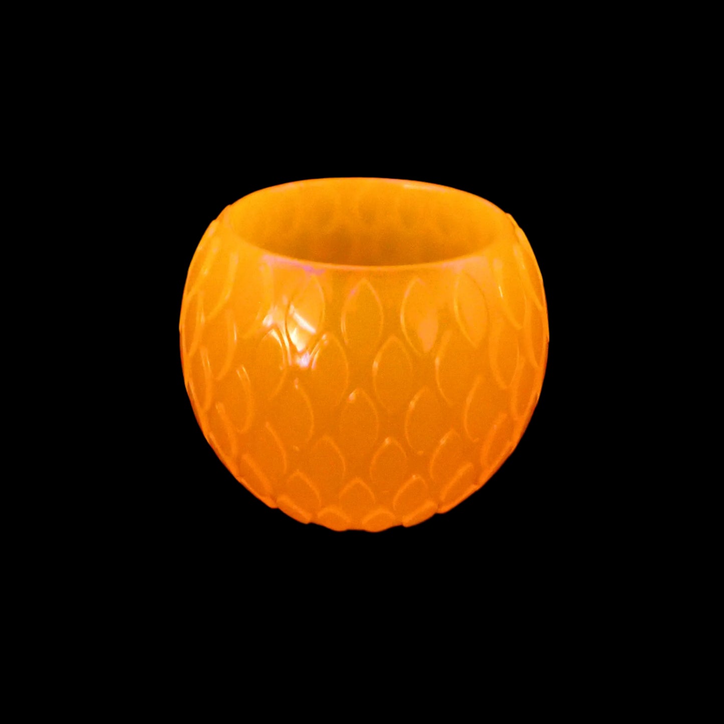 Image of the handmade neon orange resin decorative bowl under a UV light showing that it fluoresces bright orange.