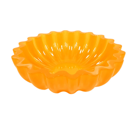 Angled view of the handmade neon orange resin scalloped bowl. It is round with a flat scalloped top edge and fluted sides. The resin is shiny and semi translucent in a citrus neon orange color. Great for using as a trinket bowl, a succulent planter pot, part of your table centerpiece, or just added to your decor. 