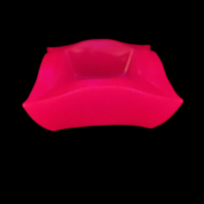 Image of the large handmade neon pink resin retro atomic style decorative bowl under a UV light showing that it is fluorescent and glowing a bright pink in color.