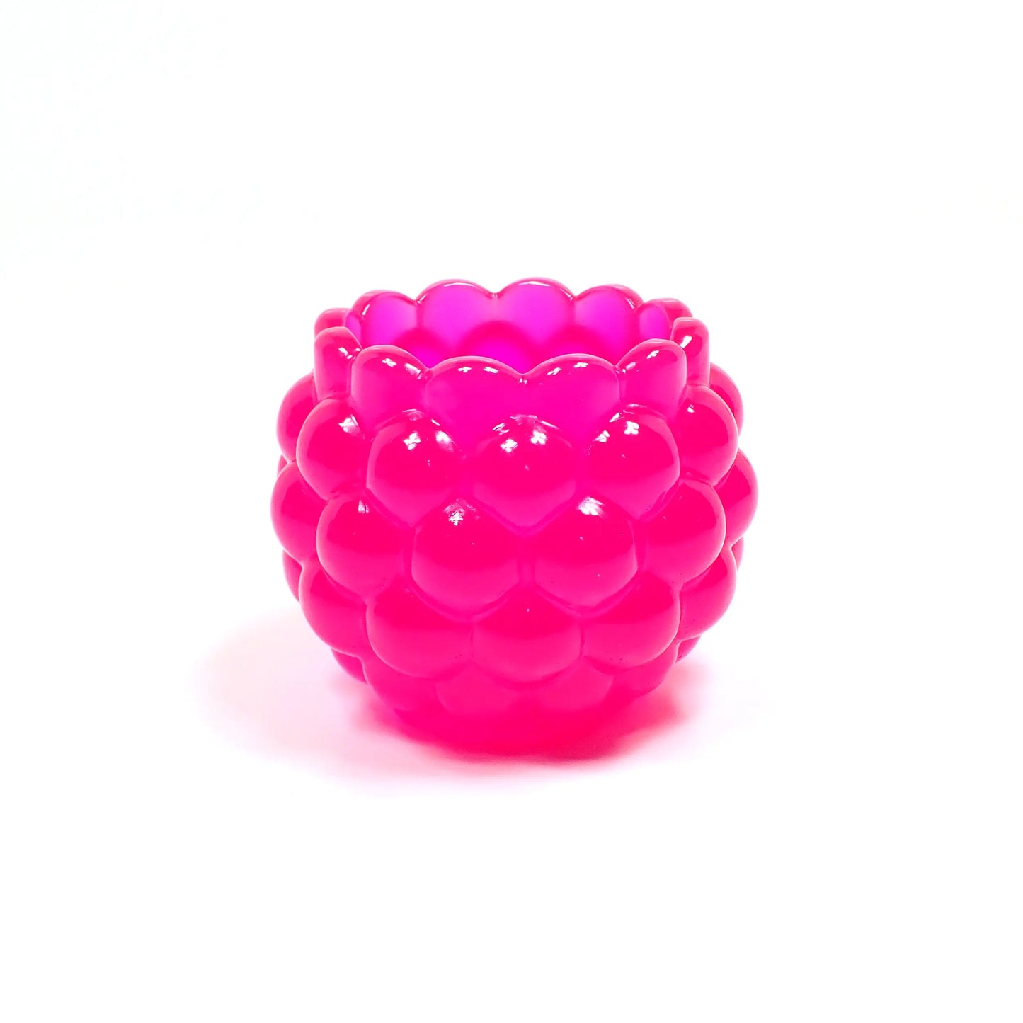 Another side view of the handmade resin bowl in neon pink. It has a bumpy round design with scalloped top.