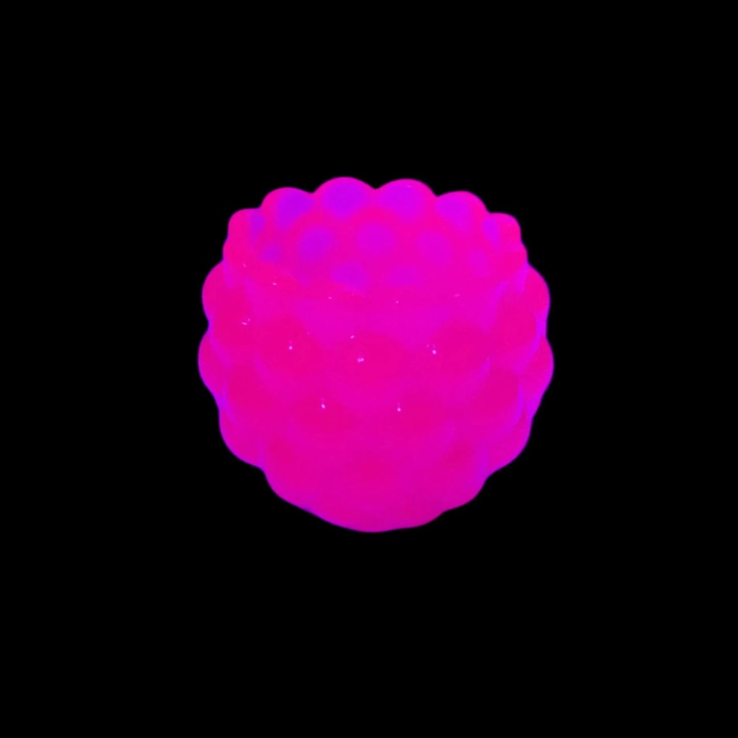 Photo showing how the neon pink decorative bowl fluoresces under a black light in a bright pink color. The background is black.