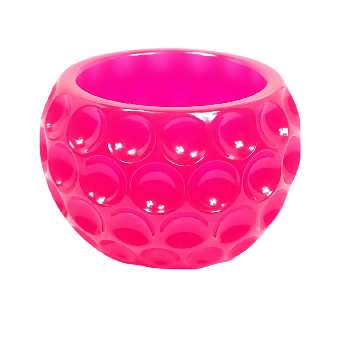 Angled side view of the handmade neon pink resin decorative bowl. It is bright pink with a rounded design that has indented dots all the way around it.