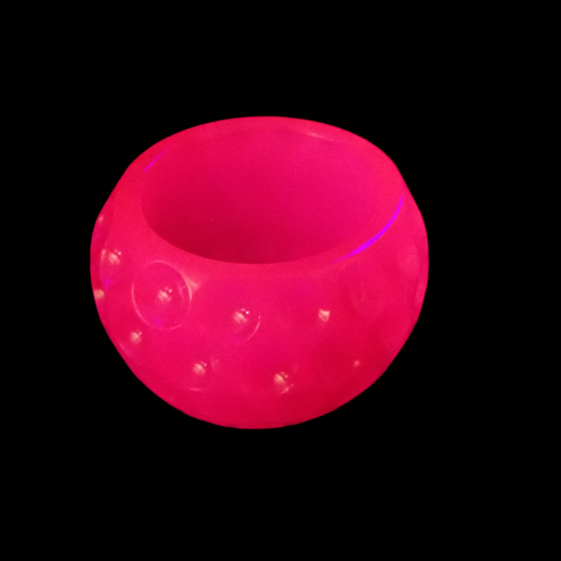 Photo showing the neon pink dotted bowl fluorescing under a UV light in bright pink.