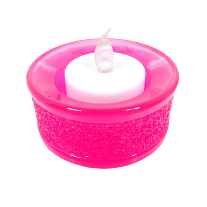 Image of the handmade bright neon pink resin tealight candle holder with a flameless LED tea light candle displayed in it.