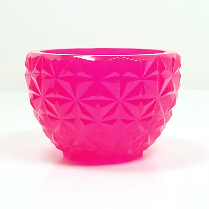 Side view of the handmade pink neon faceted bowl showing the faceted design. It has square like sections with a star like faceted pattern in each one.