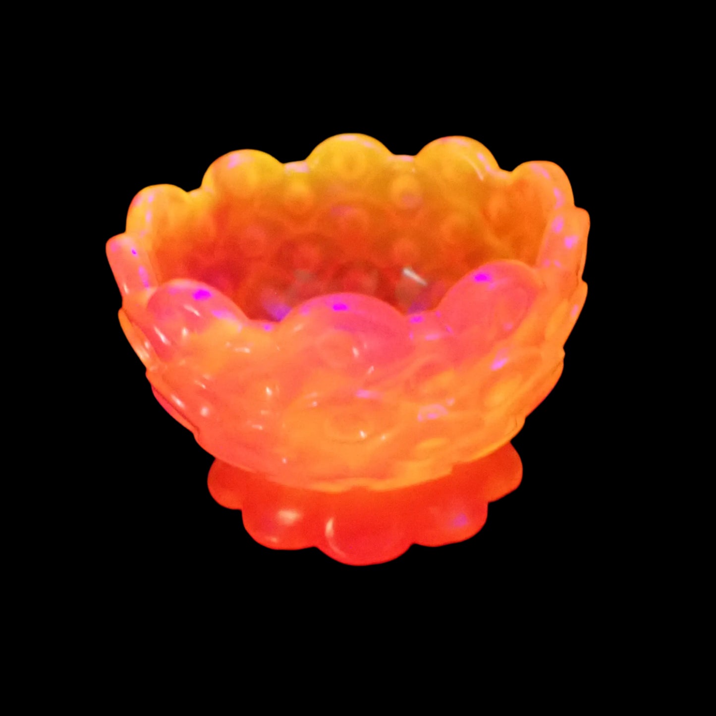 Photo of the bowl under a UV light showing how it fluoresces in bright pink and orange.