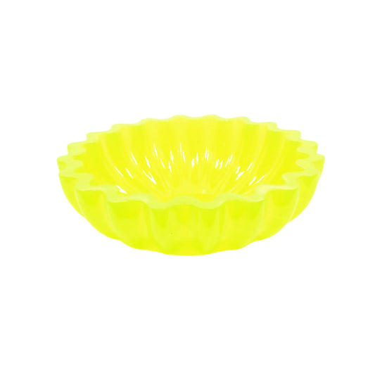 Angled side view of the handmade neon yellow resin fluted decorative bowl with scalloped edge. The bottom is tapered and the sides are fluted. The top edge is scalloped. The resin is shiny and semi translucent in a bright neon yellow color that has a tint of bright green as the light hits it.