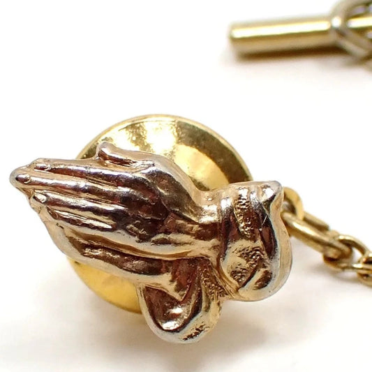 Front view of the Mid Century vintage Christian religious tie tack. It is shaped like a pair of praying hands. The metal is gold tone in color.