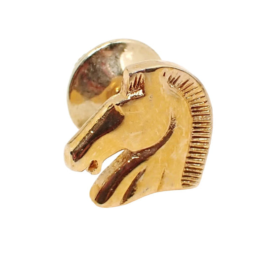 Enlarged front view of the retro vintage Avon tie tack pin. It is gold tone in color and shaped like a horses head.