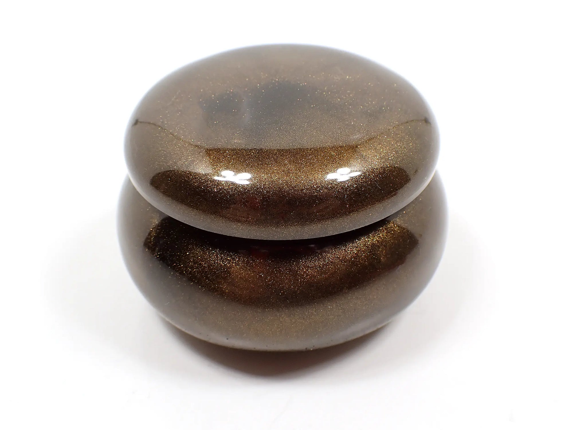 Side view of the smaller sized handmade resin trinket box. It has a rounded wide jar like shape with a round lid. The resin is pearly chocolate brown in color.