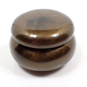 Side view of the smaller sized handmade resin trinket box. It has a rounded wide jar like shape with a round lid. The resin is pearly chocolate brown in color.