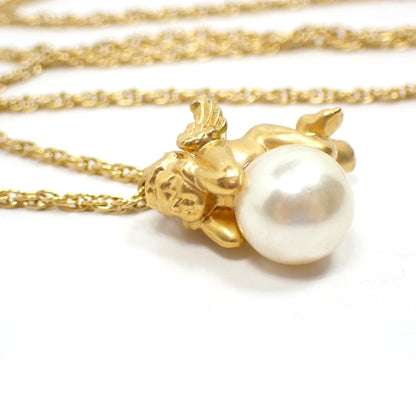 Enlarged view of the retro vintage Avon Angel pendant necklace. The metal is gold tone plated in color. The chain has a twisted rope like design. The pendant is shaped like a cherub angel resting upon an imitation pearl. The faux pearl is plastic and a pearly slightly off white color.