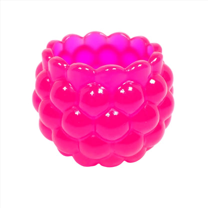 Side view of the handmade resin decorative bowl. The resin is bright neon pink in color. It has a rounded shape with a bumpy round ball textured on the outside. The top tapers slightly and has a scalloped edge.