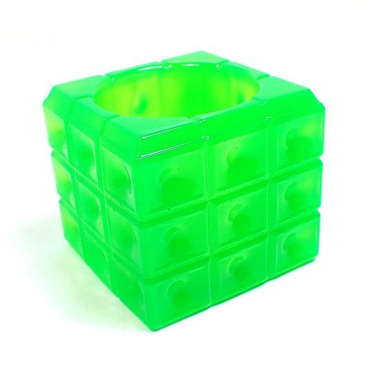 Angled photo of the handmade resin trinket dish. The resin is neon green in color. The dish is cube shaped with a square pattern all the way around the edge. The top has a round open area to put small things. 