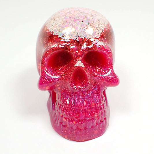 Front view of the handmade resin skull. There are two choices and this photo shows the one that has light pink iridescent glitter at the top followed by bright pink resin and iridescent glitter throughout the rest of the skull.