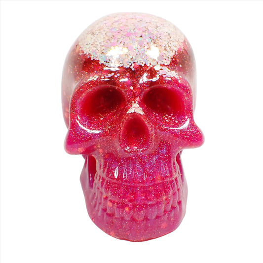 Front view of the handmade resin skull. There are two choices and this photo shows the one that has light pink iridescent glitter at the top followed by bright pink resin and iridescent glitter throughout the rest of the skull.