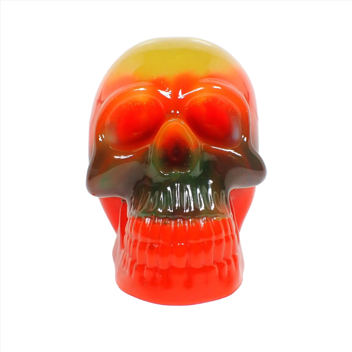 Front view of the handmade resin Neon skull. It has layered bands of color and in the photo showing regular lighting it goes from yellow, to orange, to green, to a brighter orange color.