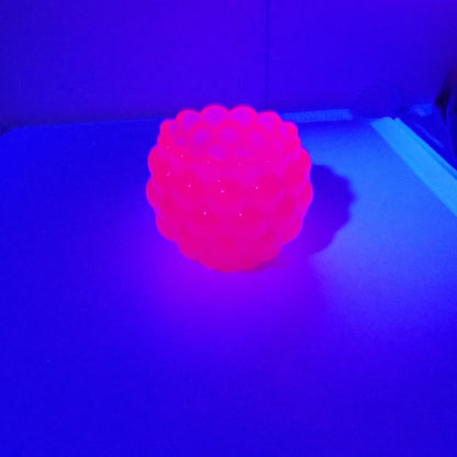 Photo showing how the handmade resin decorative bowl fluoresces under a UV light in a bright pink color. 