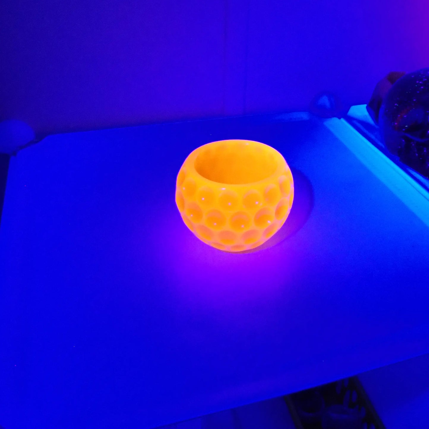 Photo showing how the handmade resin bowl fluoresces under the UV light in a bright orange color. 