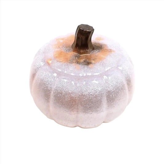 Angled view of the handmade resin pumpkin trinket box jar. The majority of it is a sparkly white color and it has small areas of peach. There is brown on the top and stem area.