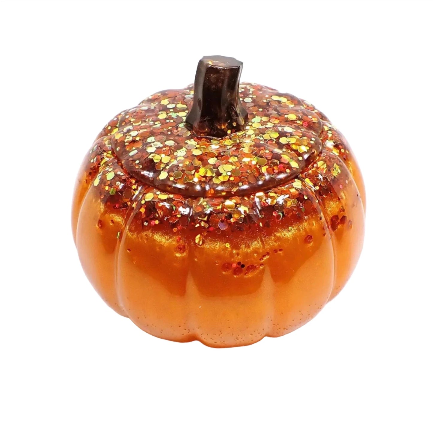 Angled view of the handmade resin pumpkin trinket box jar. The bottom of the pumpkin is pearly orange in color with flashes of metallic gold. The top has orange and pearly brown with lots of chunky iridescent glitter in Fall colors. 