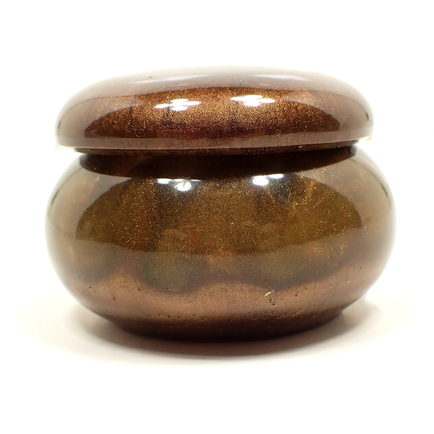 Side view of the handmade small trinket box. It has a short round jar like shape. The lid is pearly brown. The bottom part has pearly brown at the very bottom and marbled hues of gold and yellow towards the top. 