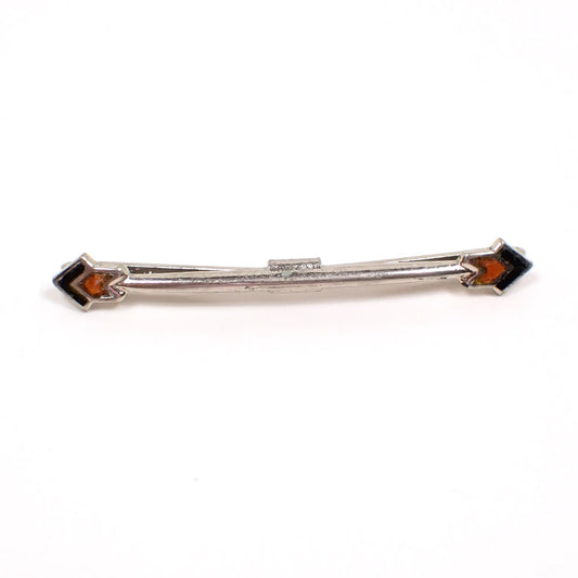 Front view of the retro vintage collar clip. The metal is silver tone in color. There are arrow head shapes at the end that are enameled with green and orange. 