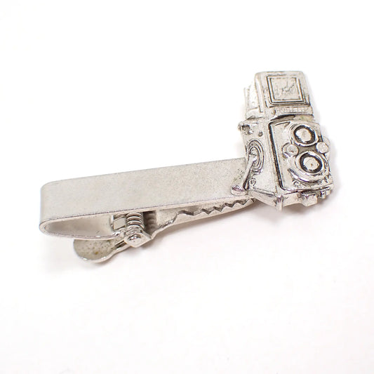 Angled view of the Mid Century vintage Rolleiflex tie clip. It is silver tone in color and has a detailed Rolleiflex camera shape at the end.