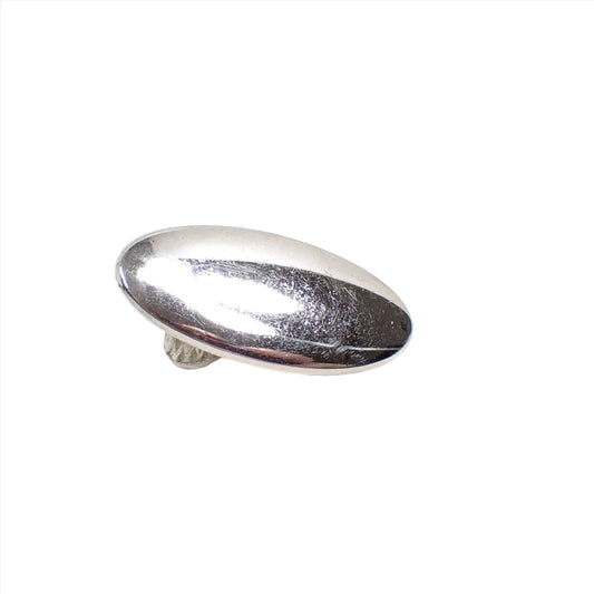 Angled view of the small Mid Century vintage Swank tie clip. It is oval in shape and silver tone in color. 