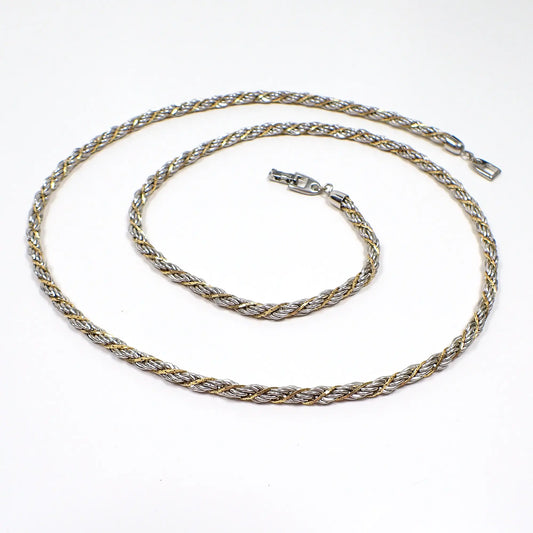 Angled top view of the retro vintage Napier chain necklace. It has a twisted rope chain design with silver tone and gold tone metal. There is a snap lock clasp at the end.