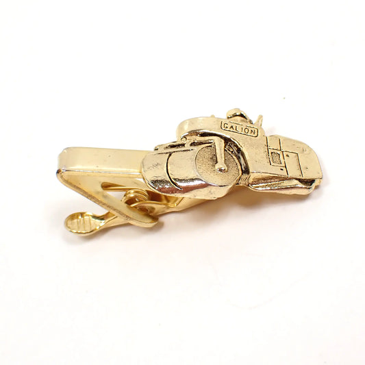 Angled view of the Mid Century vintage Mercury Industries tie clip. The metal is gold tone in color. It has a detailed tandem steam roller design on the end with company name Galion at the top.