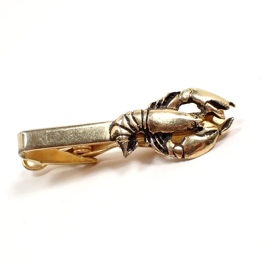 Front view of the Jolle Mid Century vintage tie clip clasp. The metal is gold tone in color. There is a lobster or crayfish style design on the end.