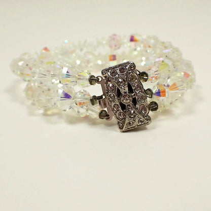 Front view of the Mid Century vintage multi strand AB crystal beaded bracelet. There are faceted round and saucer shaped glass crystal beads with a flashy multi color aurora borealis coating. There is a large rectangle box clasp at the end that has clear round rhinestones on the top. 