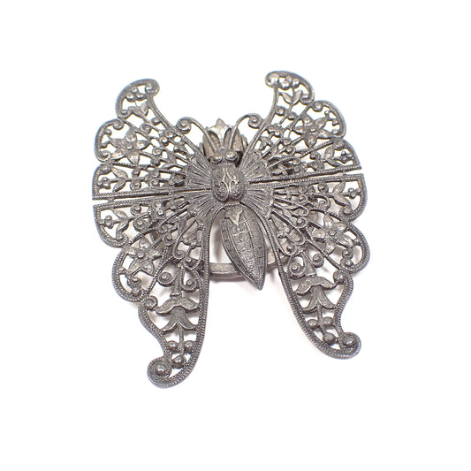 Front view of the 1940's Mid Century vintage filigree scarf clip. It is dark gray in color from age. It's shaped like a butterfly with a very detailed filigree floral design on the wings. 