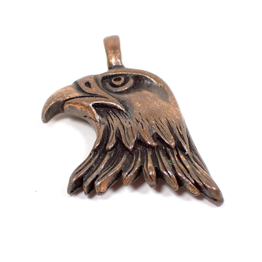 Front view of the retro vintage antiqued copper pendant. It is shaped like an eagle's head and has a loop bail attached to the top.