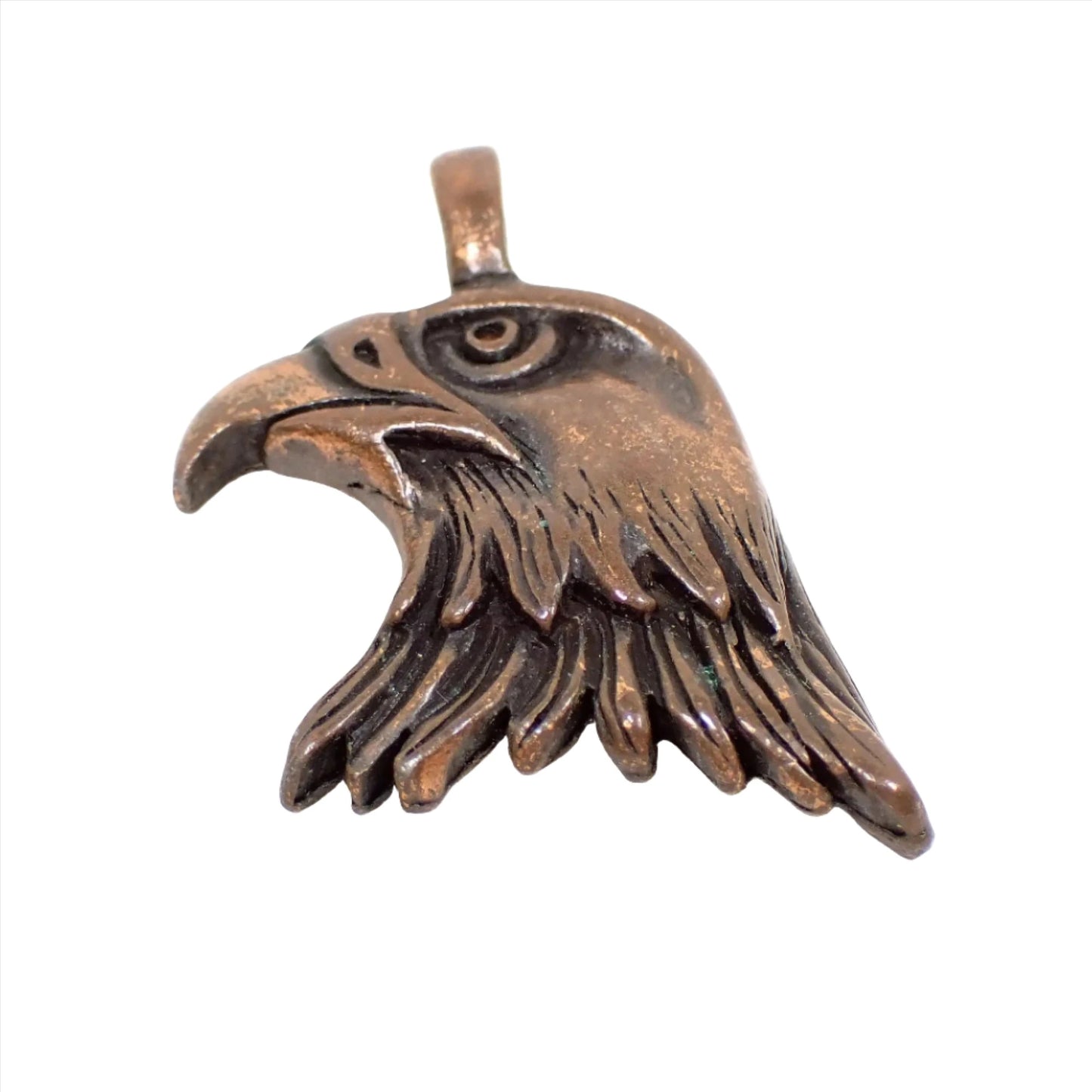 Front view of the retro vintage antiqued copper pendant. It is shaped like an eagle's head and has a loop bail attached to the top.