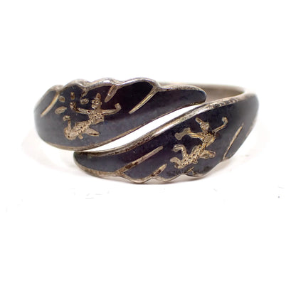 Front view of the Mid Century vintage Siam sterling ring. It has a bypass design with wing like shaped ends.  There is black enamel on the front with etched Siam dancers. 