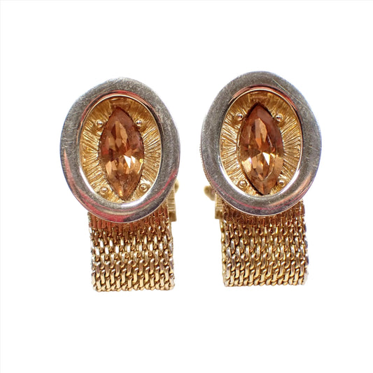 Front view of the Swank Mid Century vintage wrap around mesh cufflinks. The metal is gold tone in color. There are ovals in the front with textured ovals behind it. In the middle are marquis cut light brown rhinestones.