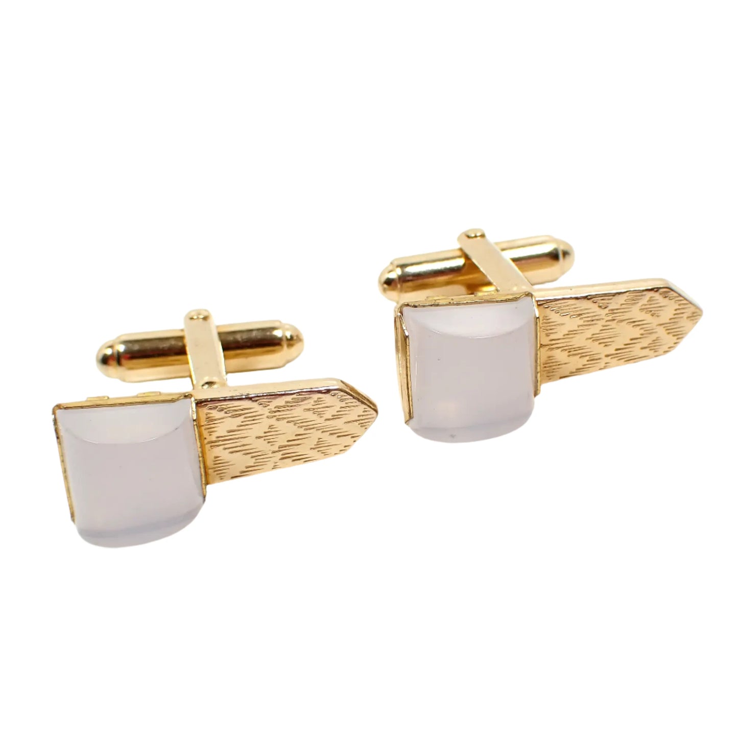 Front view of the Mid Century Vintage Anson cufflinks. The cuff links are gold tone in color. They are shaped like a sideways tie with a textured diamond pattern on the metal. The ends have semi translucent white lucite cabs that are domed cylinder shaped.