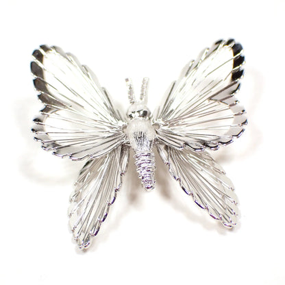 Top view of the Monet retro vintage brooch pin. It is shaped like a butterfly with wire wrapping around the wings. The metal is silver tone in color.