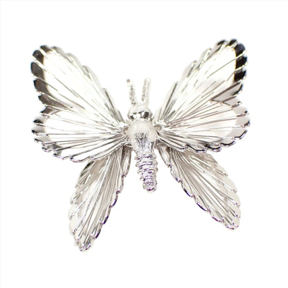 Top view of the Monet retro vintage brooch pin. It is shaped like a butterfly with wire wrapping around the wings. The metal is silver tone in color.